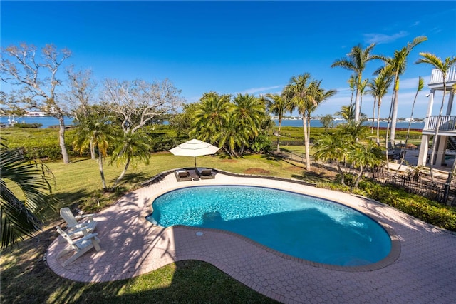 outdoor pool with a yard, a patio area, and a water view