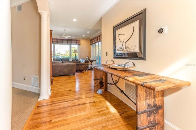 hall featuring visible vents, baseboards, light wood-type flooring, and ornate columns