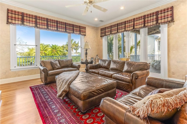 living room with visible vents, a ceiling fan, wood finished floors, crown molding, and baseboards