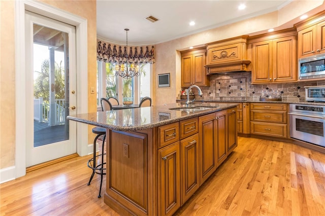 kitchen featuring a sink, stainless steel appliances, visible vents, and brown cabinetry