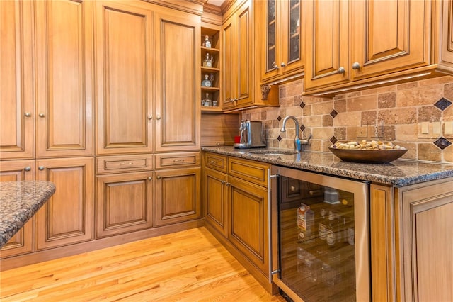 kitchen featuring a sink, backsplash, beverage cooler, and brown cabinetry