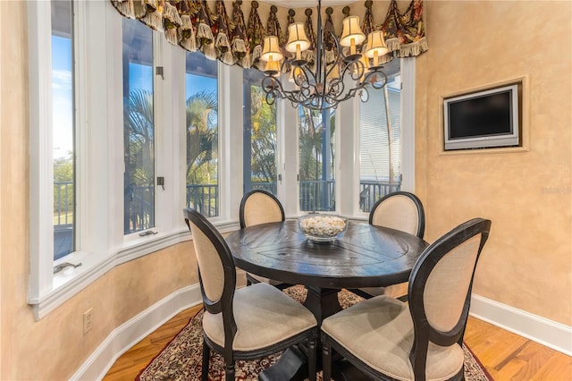 dining area with baseboards, an inviting chandelier, and wood finished floors