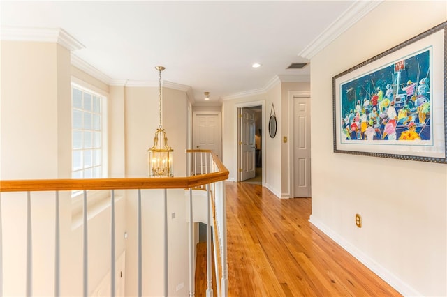 hall with visible vents, crown molding, baseboards, light wood-type flooring, and a notable chandelier