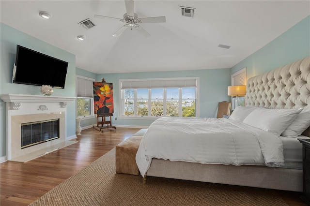 bedroom with vaulted ceiling, visible vents, a fireplace, and wood finished floors