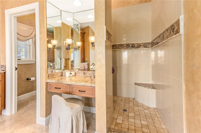 bathroom with baseboards, vanity, and a walk in shower