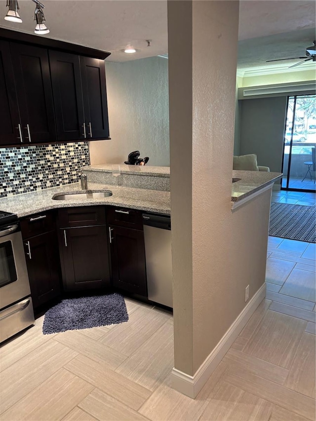 kitchen with stainless steel appliances, tasteful backsplash, a ceiling fan, a sink, and dark cabinetry