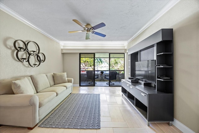 living room with a textured ceiling, ceiling fan, baseboards, and ornamental molding