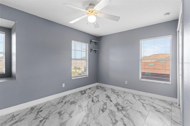 unfurnished room with baseboards, a textured ceiling, marble finish floor, and ceiling fan