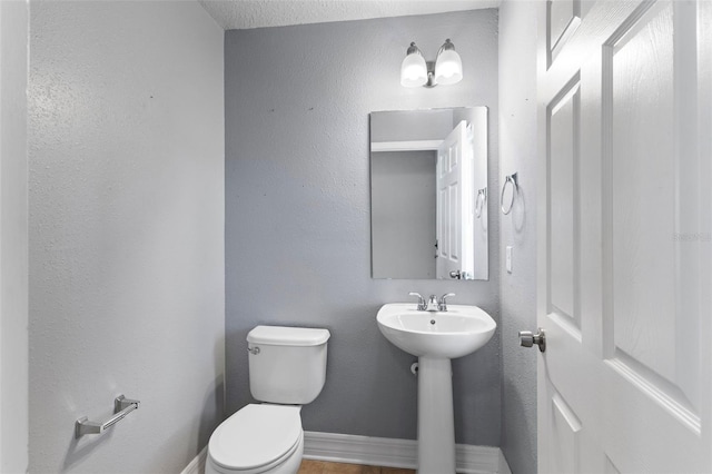 bathroom featuring toilet, baseboards, and a sink