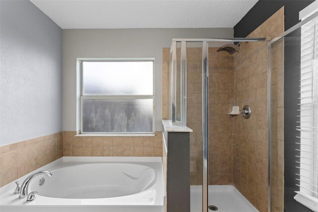 bathroom with a textured ceiling, a stall shower, and a bath