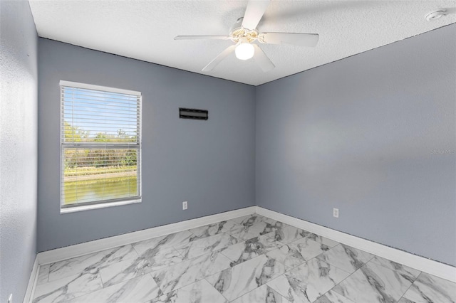 spare room featuring marble finish floor, a textured ceiling, baseboards, and ceiling fan