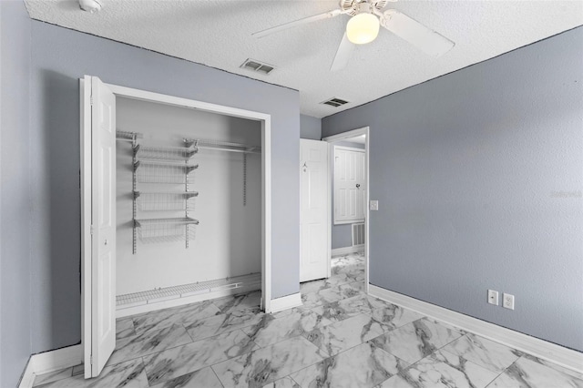 unfurnished bedroom with visible vents, marble finish floor, a textured ceiling, baseboards, and ceiling fan