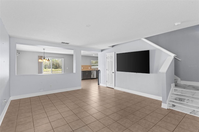 unfurnished living room featuring tile patterned flooring, visible vents, baseboards, a chandelier, and stairway