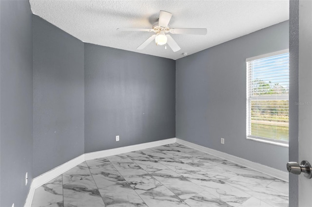 unfurnished room with baseboards, a textured ceiling, marble finish floor, and ceiling fan