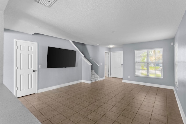 unfurnished living room featuring stairs, baseboards, visible vents, and a textured ceiling