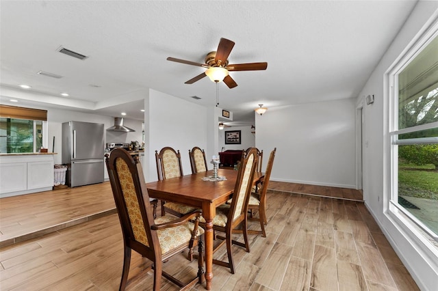 dining space with a healthy amount of sunlight, light wood finished floors, visible vents, and a ceiling fan