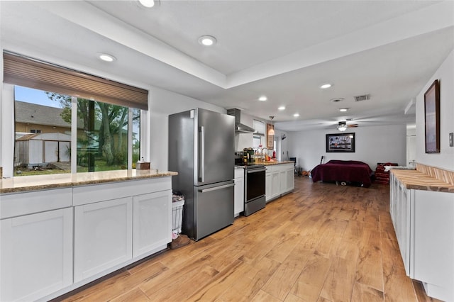 kitchen featuring range with electric stovetop, visible vents, light wood-style floors, wall chimney range hood, and freestanding refrigerator