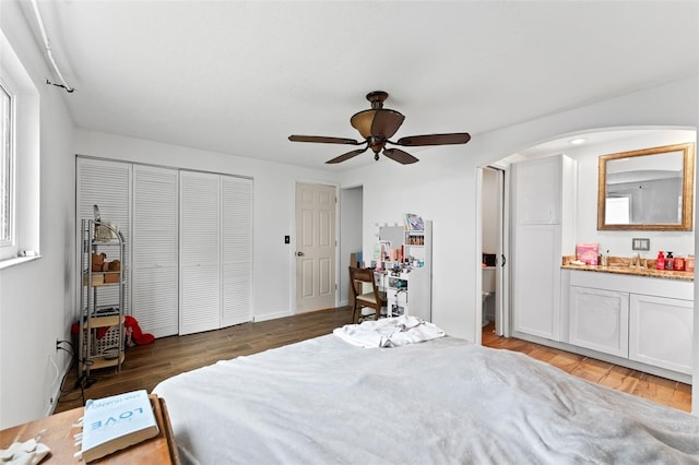 bedroom with arched walkways, a closet, a sink, and light wood-style flooring