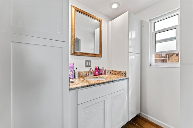 bathroom with recessed lighting, wood finished floors, vanity, and baseboards