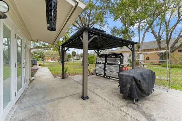 view of patio featuring driveway, a grill, fence, and a gazebo