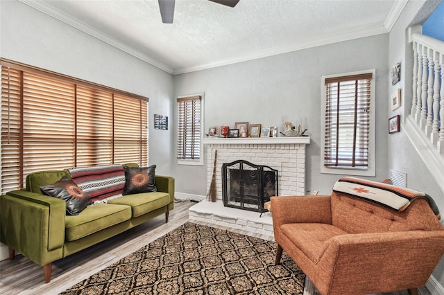 living area featuring wood finished floors, baseboards, a textured ceiling, crown molding, and a brick fireplace