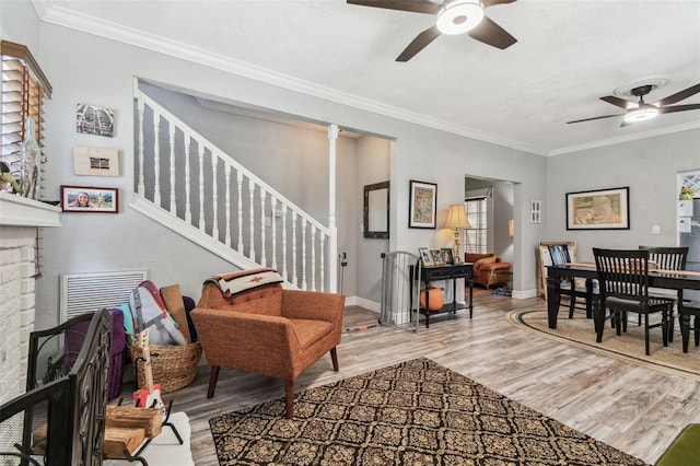 living area with stairs, a ceiling fan, wood finished floors, and ornamental molding