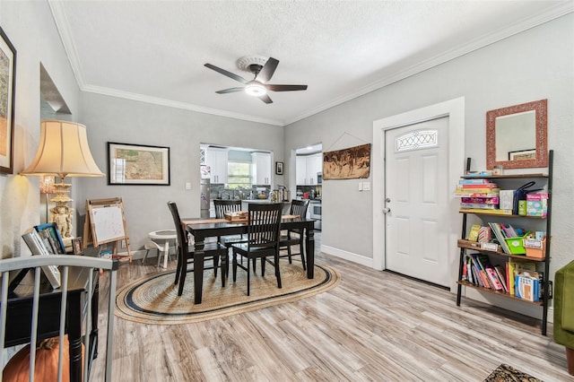 dining area with ceiling fan, baseboards, ornamental molding, wood finished floors, and a textured ceiling