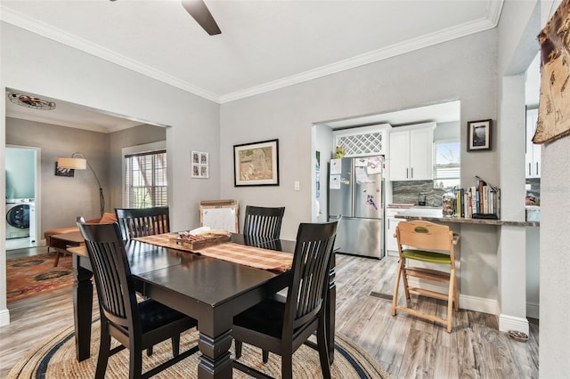 dining space with a ceiling fan, baseboards, light wood-style flooring, washer / clothes dryer, and ornamental molding