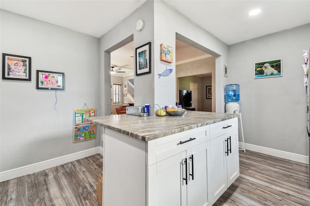 kitchen featuring light wood-style flooring, a ceiling fan, baseboards, and white cabinets