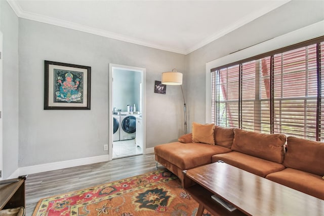 living area with washer and dryer, crown molding, baseboards, and wood finished floors