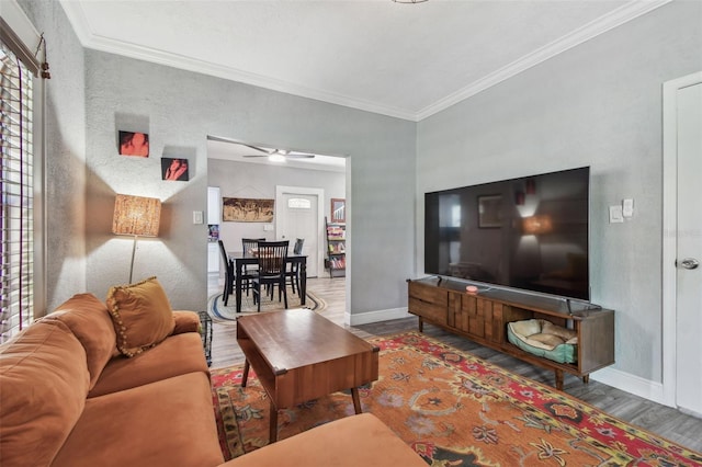 living room with ornamental molding, a ceiling fan, baseboards, and wood finished floors