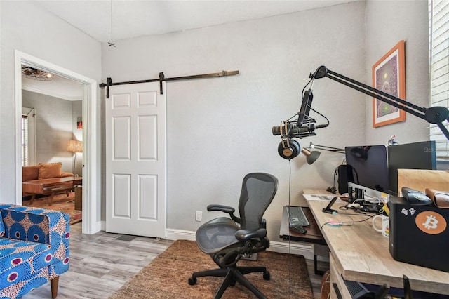 office area featuring baseboards, a barn door, and wood finished floors