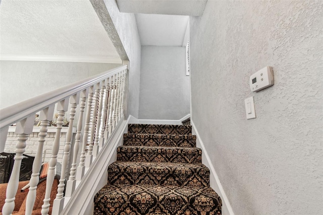 staircase featuring baseboards and a textured wall