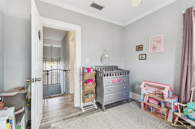 playroom with visible vents, baseboards, wood finished floors, and crown molding