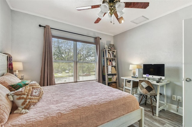 bedroom with a ceiling fan, crown molding, wood finished floors, and baseboards