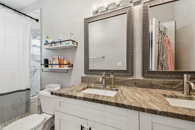 full bathroom featuring a sink, toilet, double vanity, and a textured wall