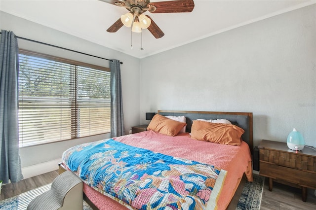 bedroom with baseboards, crown molding, ceiling fan, and wood finished floors