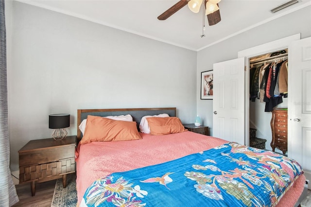 bedroom with wood finished floors, visible vents, a spacious closet, a closet, and crown molding