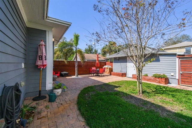 view of yard featuring an outdoor structure, a patio, and fence