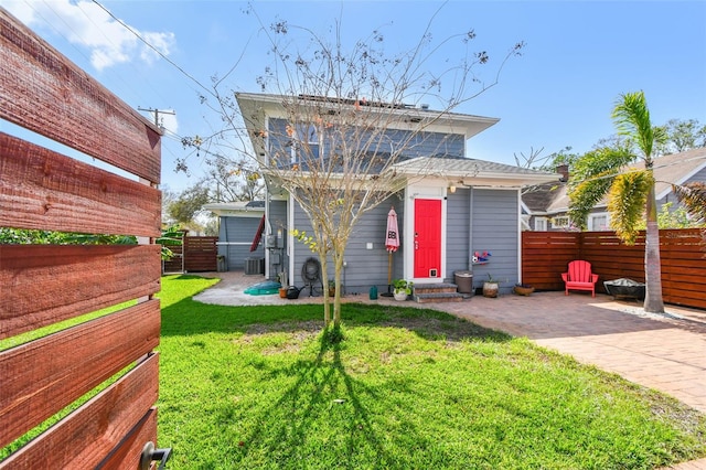 rear view of house with a patio, central air condition unit, a yard, and fence