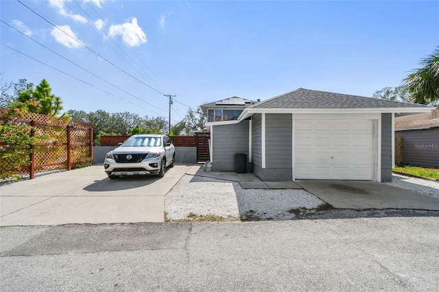 view of home's exterior with driveway, roof with shingles, and fence