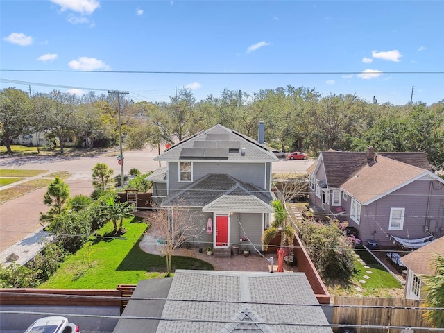 view of front of home with a front yard, fence, and roof mounted solar panels