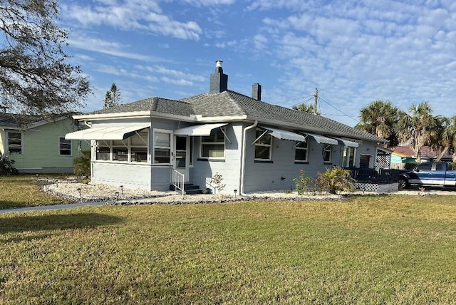 view of front of home featuring entry steps, roof with shingles, a chimney, and a front yard