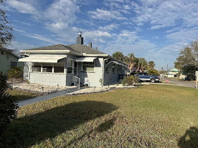 exterior space featuring a front yard, concrete block siding, and a chimney