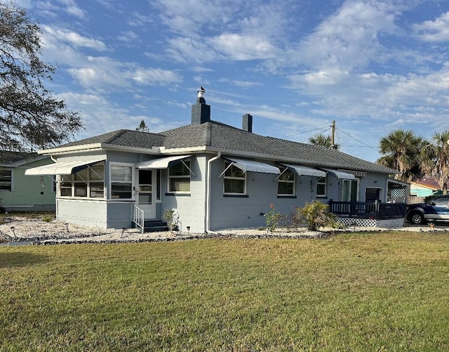 back of property featuring roof with shingles, a lawn, and a chimney