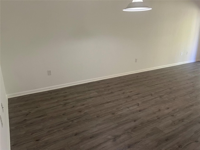 empty room with dark wood finished floors and baseboards