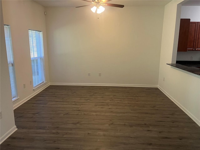 empty room with ceiling fan, dark wood-style flooring, and baseboards