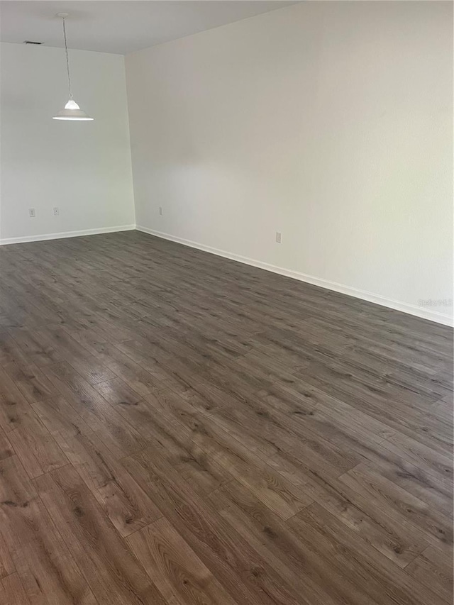 spare room featuring dark wood-type flooring and baseboards