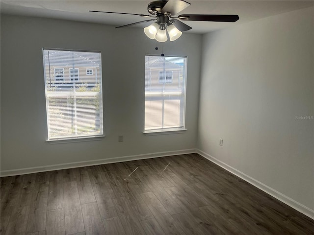 unfurnished room featuring baseboards, dark wood finished floors, and a wealth of natural light