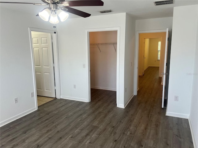 unfurnished bedroom featuring a spacious closet, visible vents, dark wood finished floors, and a closet